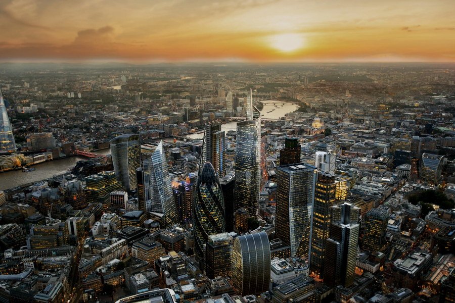 The City of London from the air at sunset, the Thames curving behind the towers.