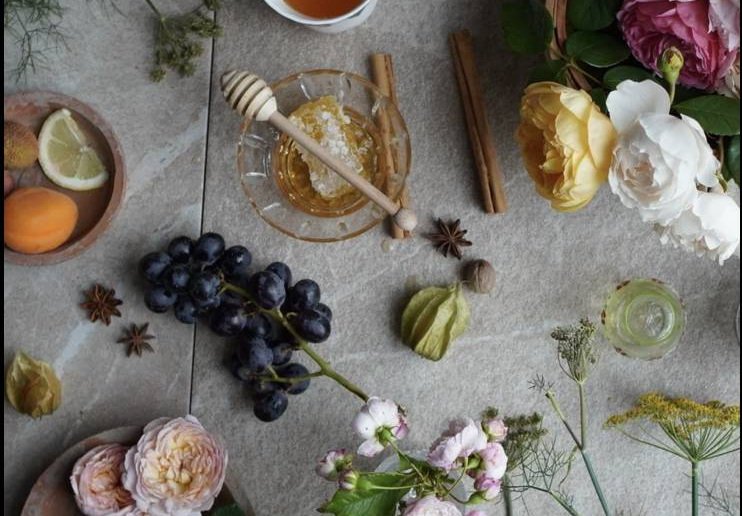 Flat-lay of raw scent materials: citrus, star anise, honey and flowers.